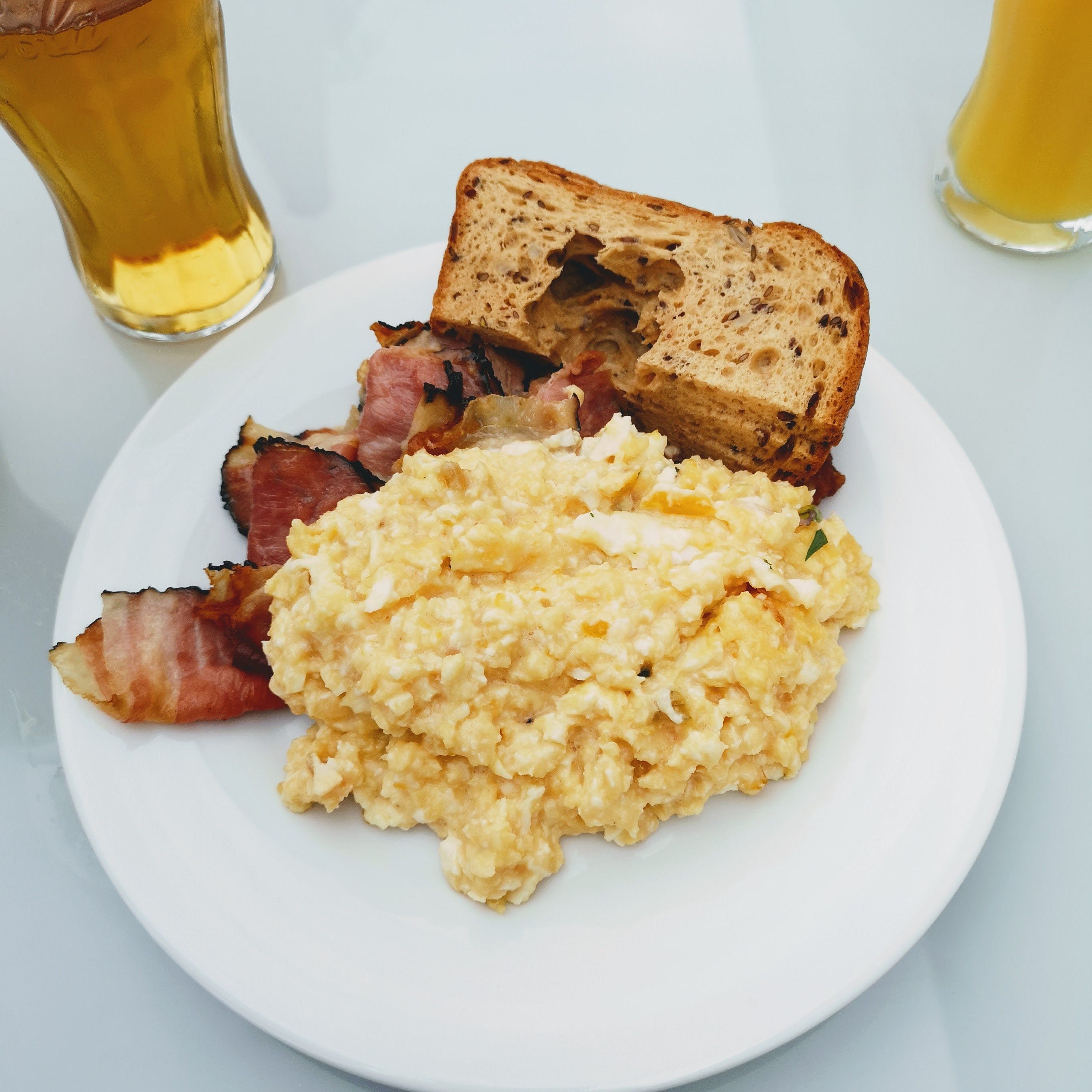 Plate of scrambled eggs, bacon and toast